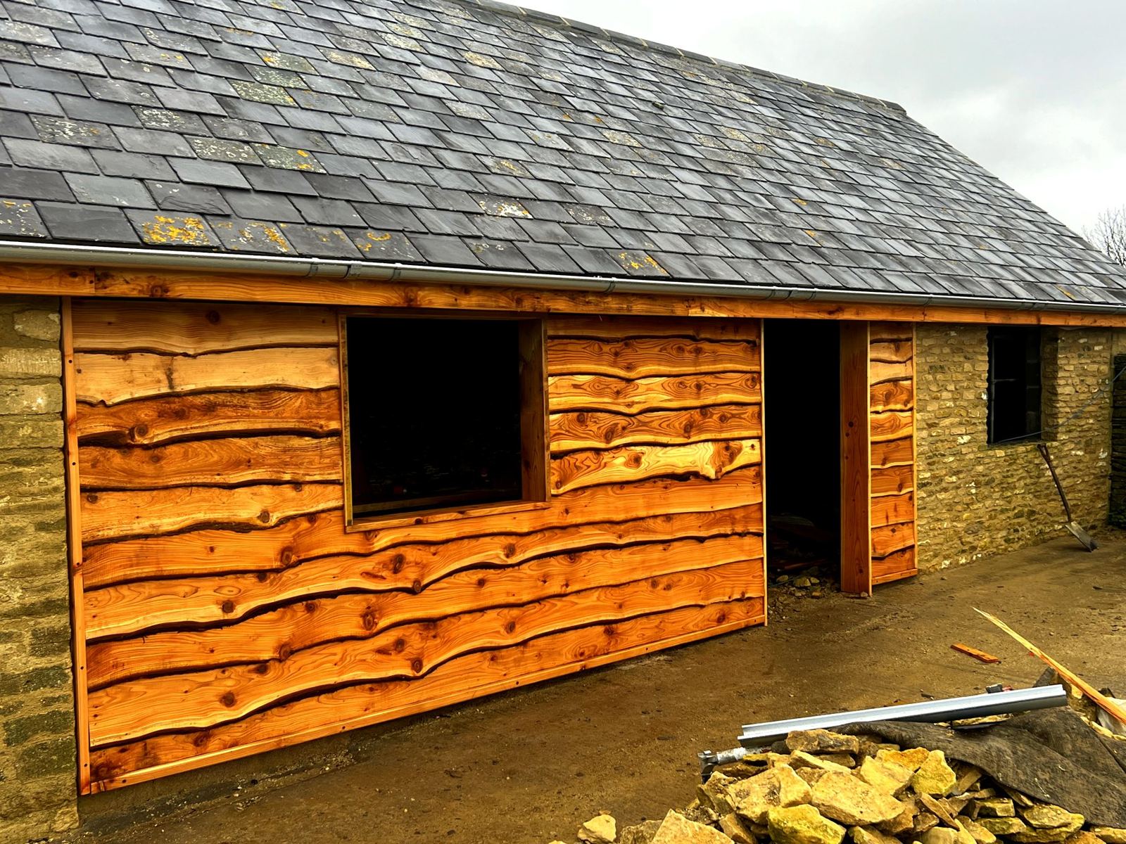 Waney-edge boards clad over a stone barn infill panel