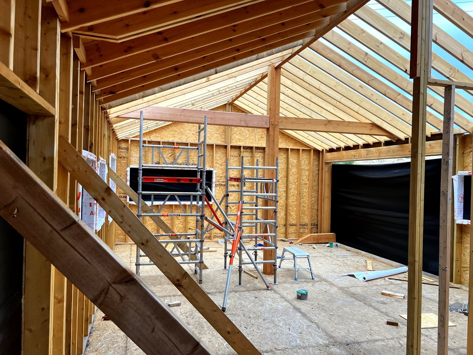 Inside a new frame: studs, rafters and ridge going up