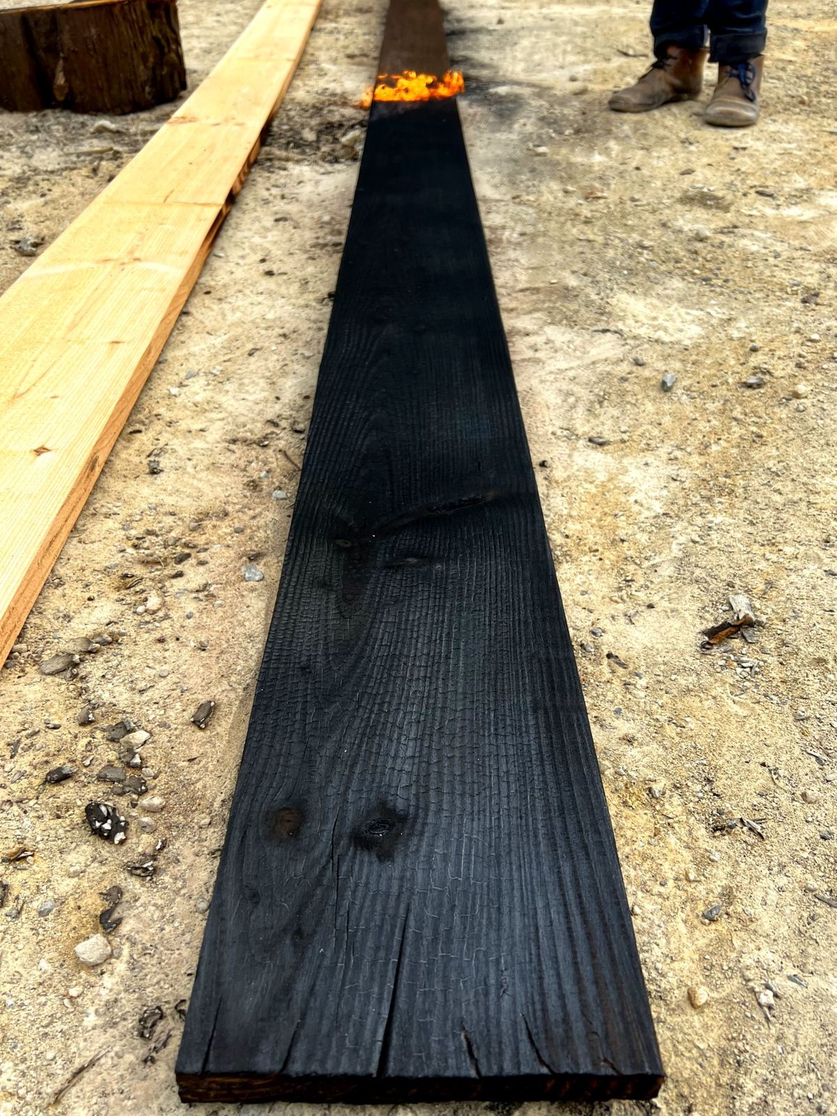 A board being charred, with flame at the far end