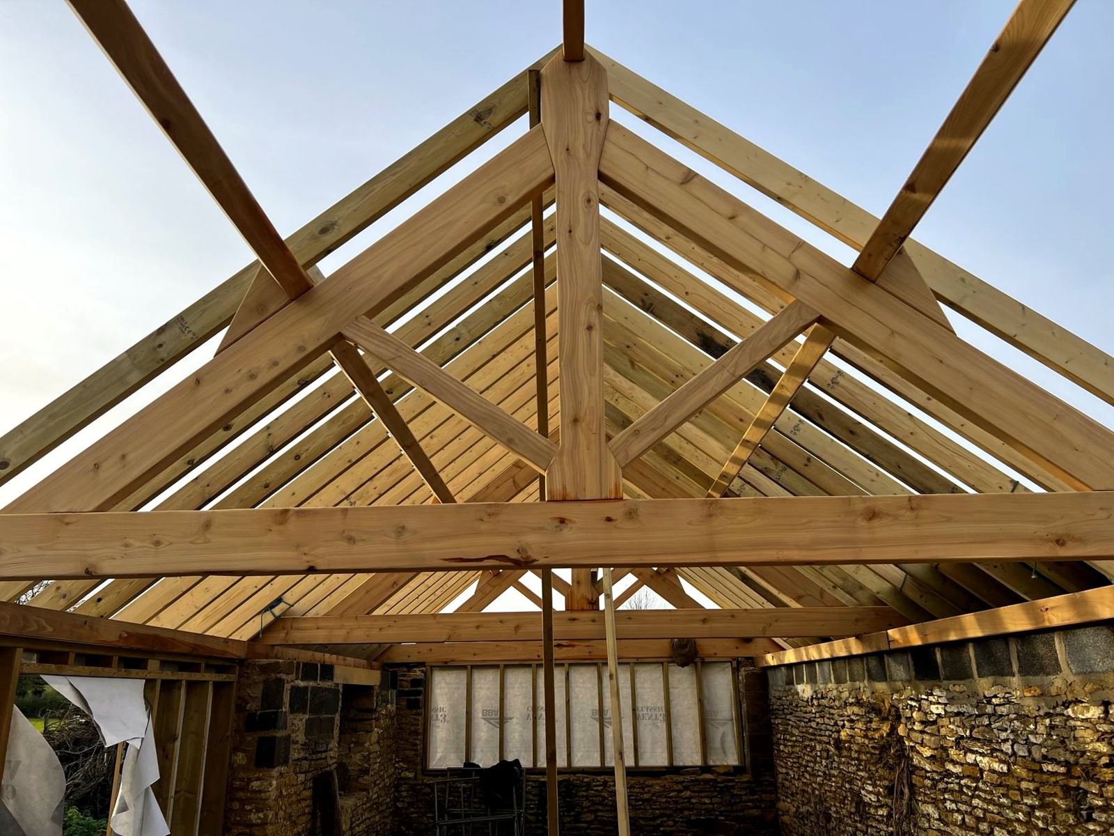 New trusses in place on the stone walls of a barn, seen from below
