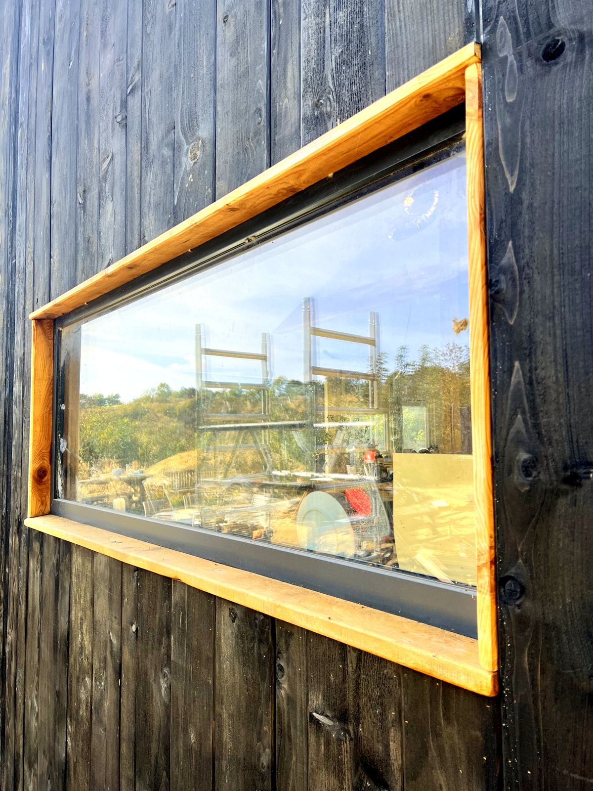 Picture window in charred cladding reflecting the quarry